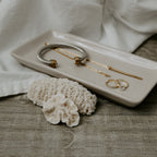 Cream stoneware tray holding bracelets and rings