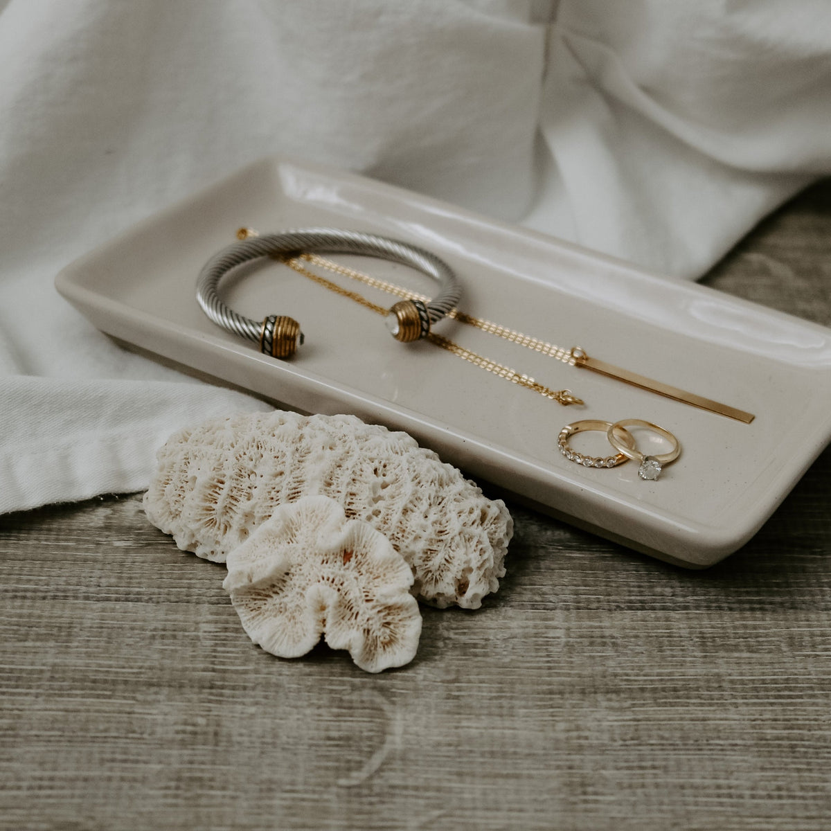 Cream stoneware tray holding bracelets and rings