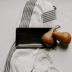 Matte black stoneware tray on a striped towel beside two pears