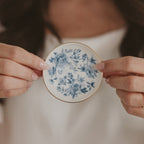 Hands holding the blue Delft floral jewelry dish