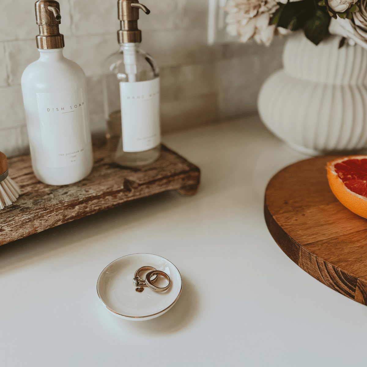 Gold heart jewelry dish holding rings beside soap dispensers on a counter