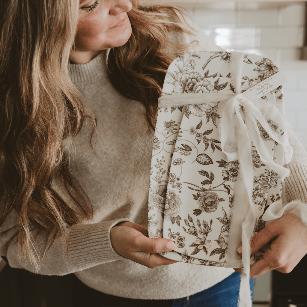 Woman holding the brown Delft melamine tray set tied with a ribbon