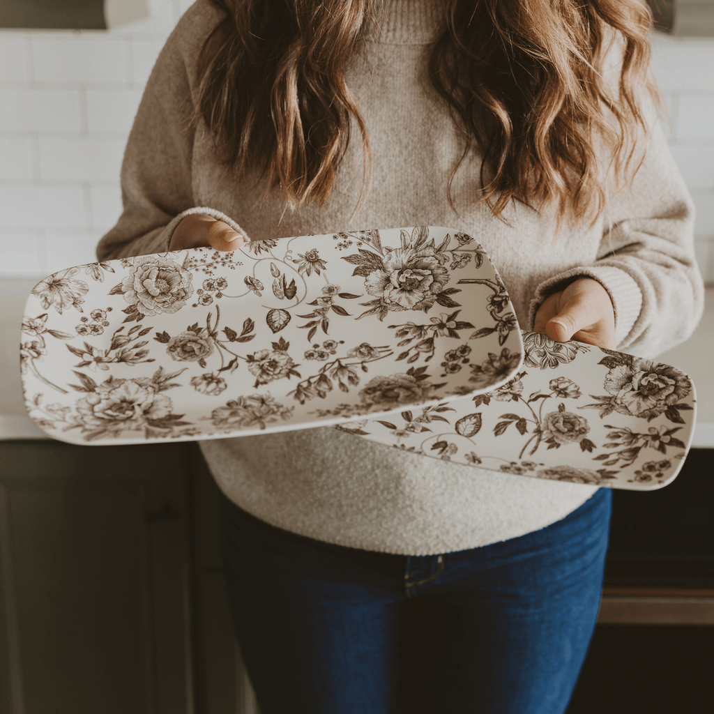 Woman holding the two brown Delft floral melamine trays