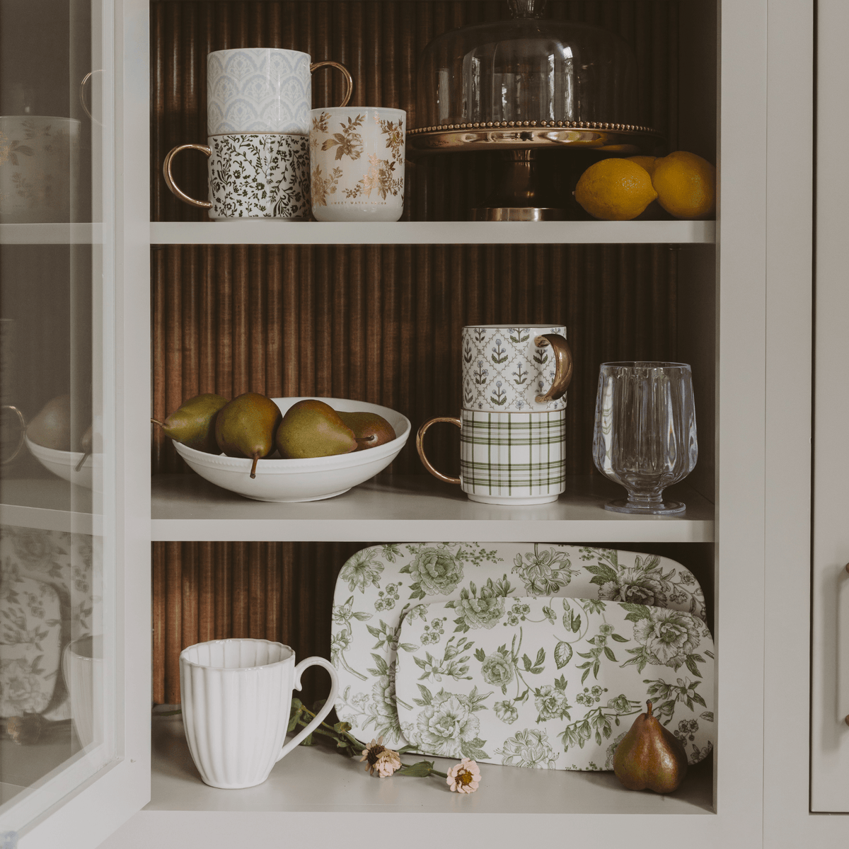Green Delft floral trays displayed on a kitchen hutch shelf beside mugs