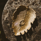 Gold leaf accessory dish holding a ring on a marble surface