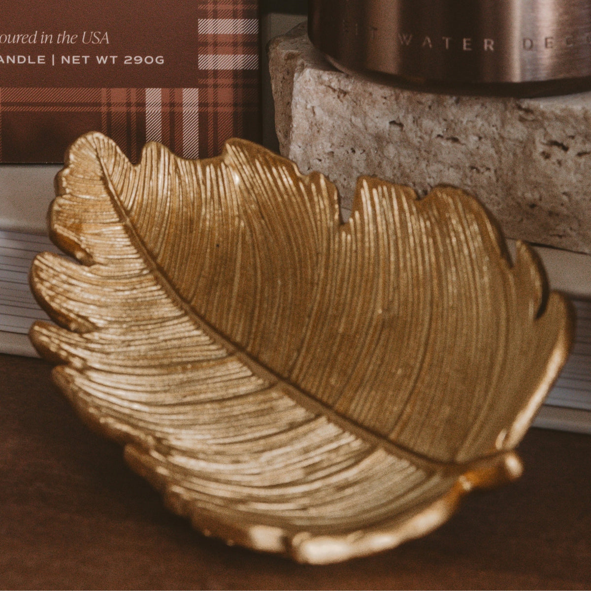 Gold leaf-shaped accessory dish on a wooden shelf