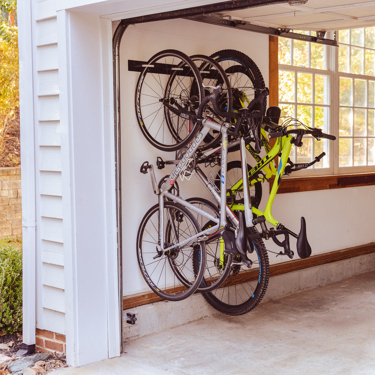Four bikes hanging on the wall rack in a garage beside the open door