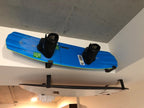 Wakeboard stored on minimalist wall hooks below a ceiling