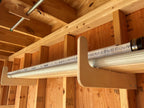 Wood bracket holding long items under a shed shelf