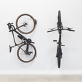Two bikes on swivel wall hooks, one swung flat against the wall