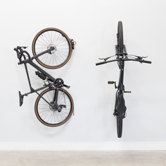 Two bikes on swivel wall hooks, one swung flat against the wall
