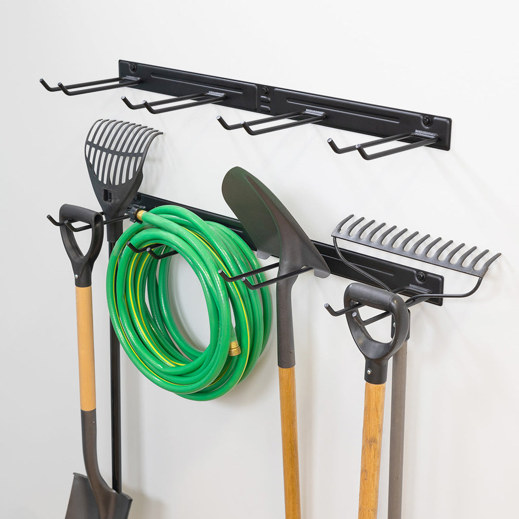 Garden tool rail holding a hose, rakes and shovels