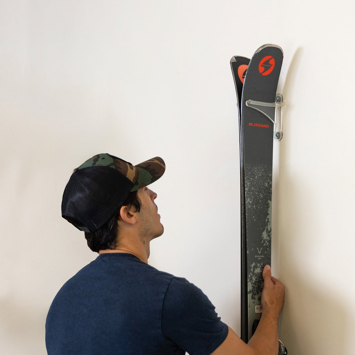 Man hanging a pair of skis on a clear acrylic rack