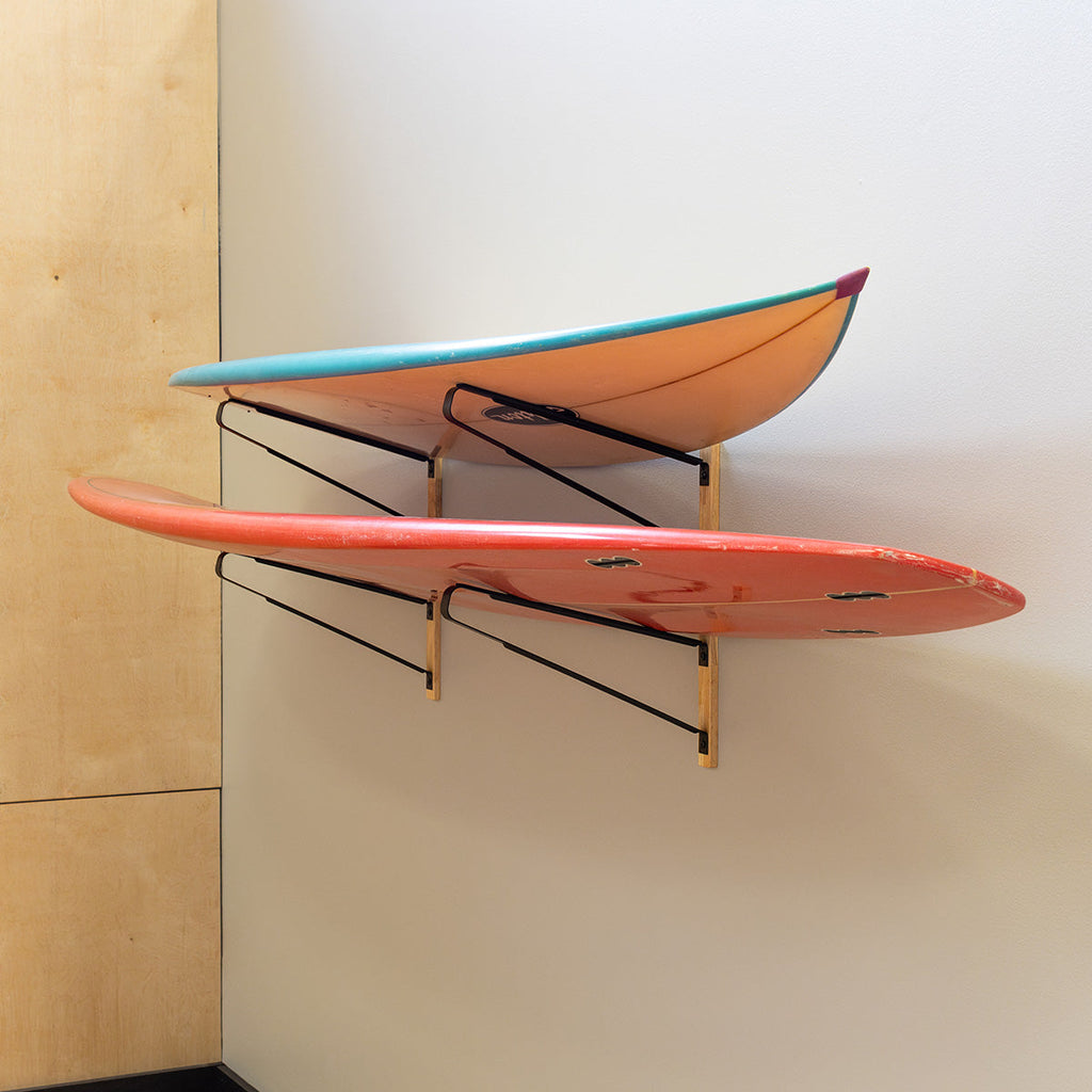 Two surfboards stored on the 2-level wall-mounted surfboard rack