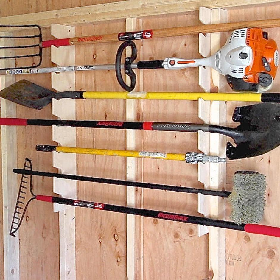 Garden tool rack holding a rake, shovel and trimmer on a shed wall