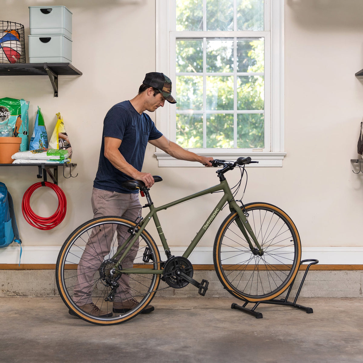 Man rolling a bike into the floor stand in a garage
