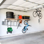 Garage wall with a long bracket shelf holding tires and bins, with bikes and a wheelbarrow hung below