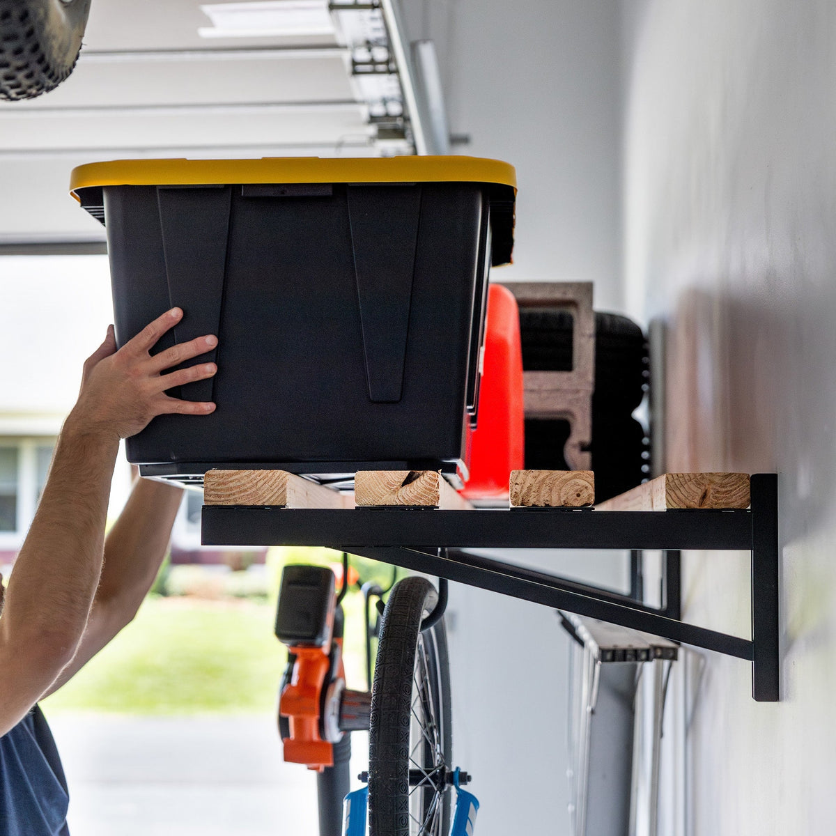 Person lifting a tote onto the long wood shelf