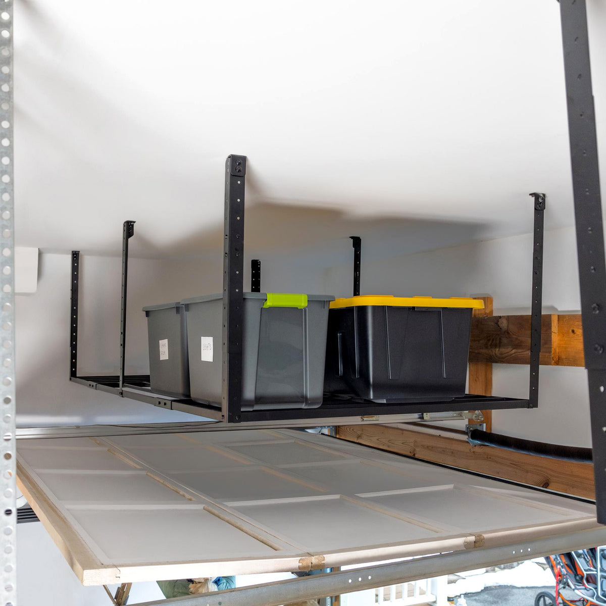 Overhead rack holding bins in the space above a garage door