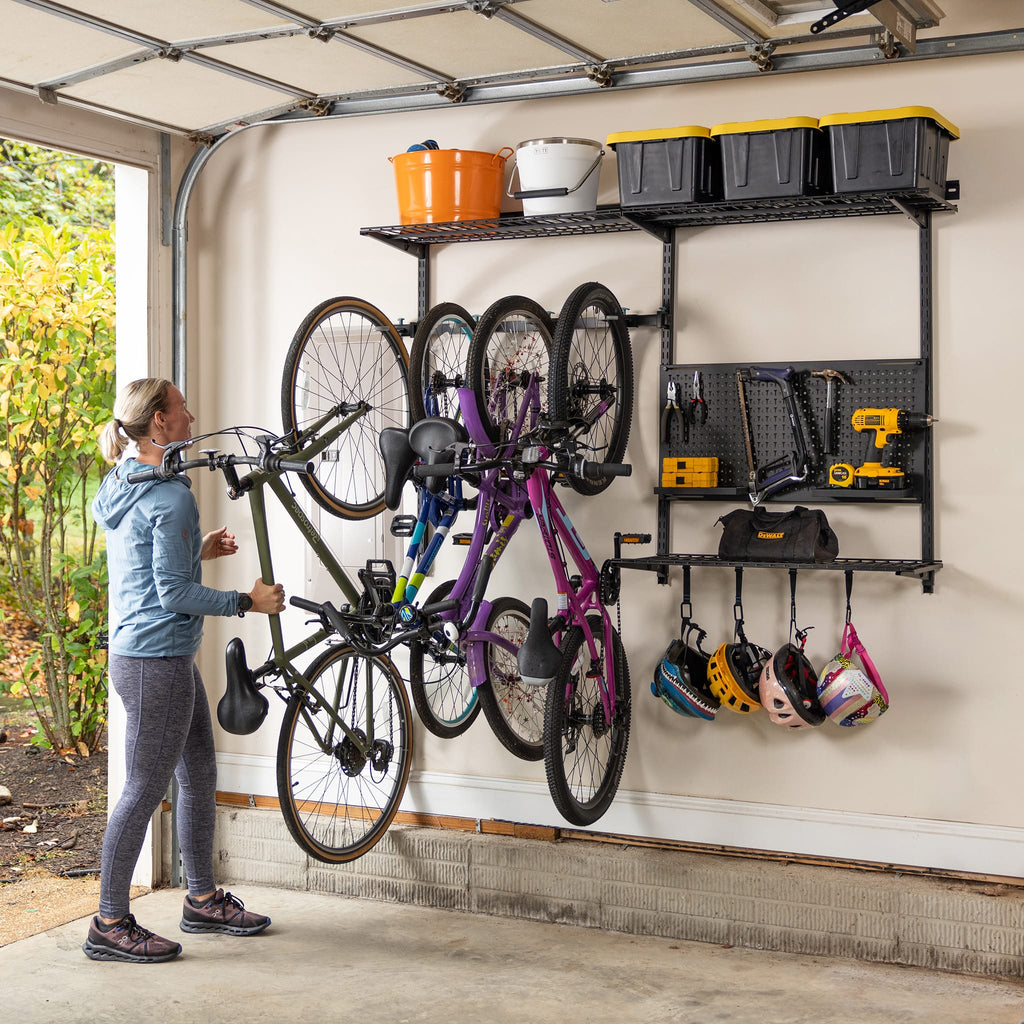 Woman hanging a bike on the G-Storage Pro wall system holding bikes, helmets, tools and bins