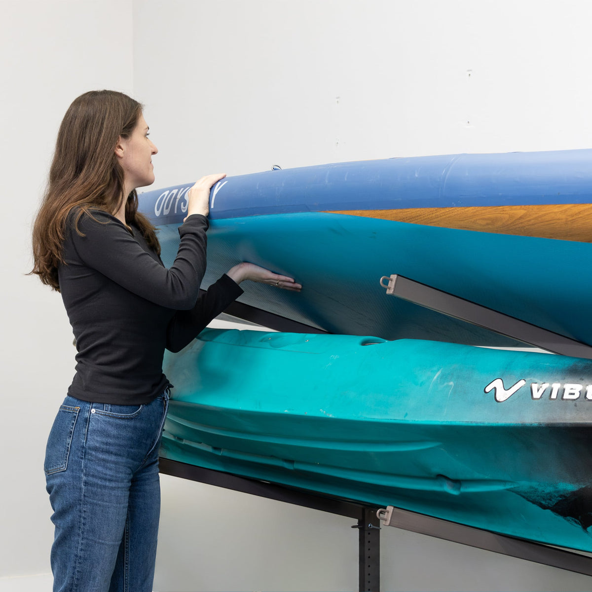 Woman sliding a kayak onto the mud-colored rolling rack