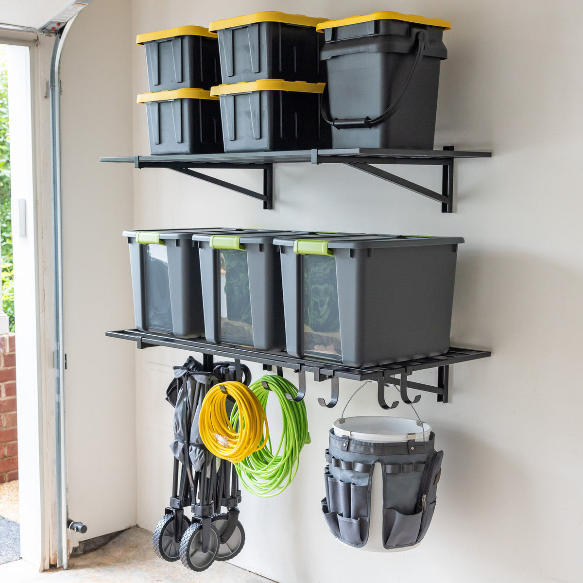 Two black 2 x 4 ft wall shelves holding storage bins, with a folding cart and buckets hung below
