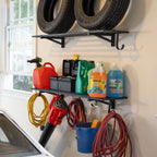 Black wall shelves holding tires, fluids and cleaning supplies with cords and a bucket hung below