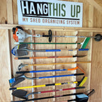 Garden tool organizer rack holding shovels, rakes and a trimmer in a shed