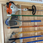 Garden tool rack holding a string trimmer, leaf blower and long-handled tools