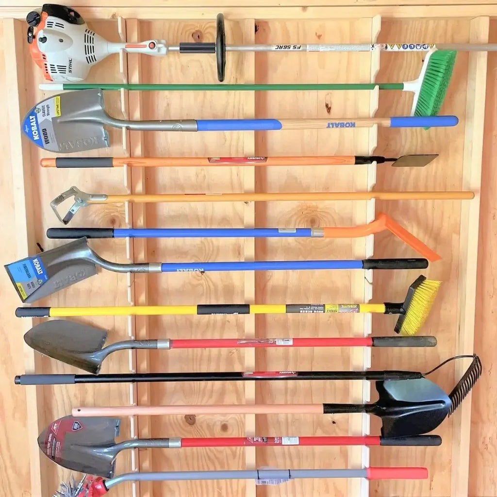 Two garden tool racks holding long-handled yard tools on a shed wall