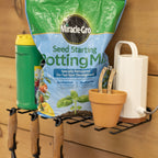 Garden tool shelf holding potting mix, a pot and watering can with tools hung underneath