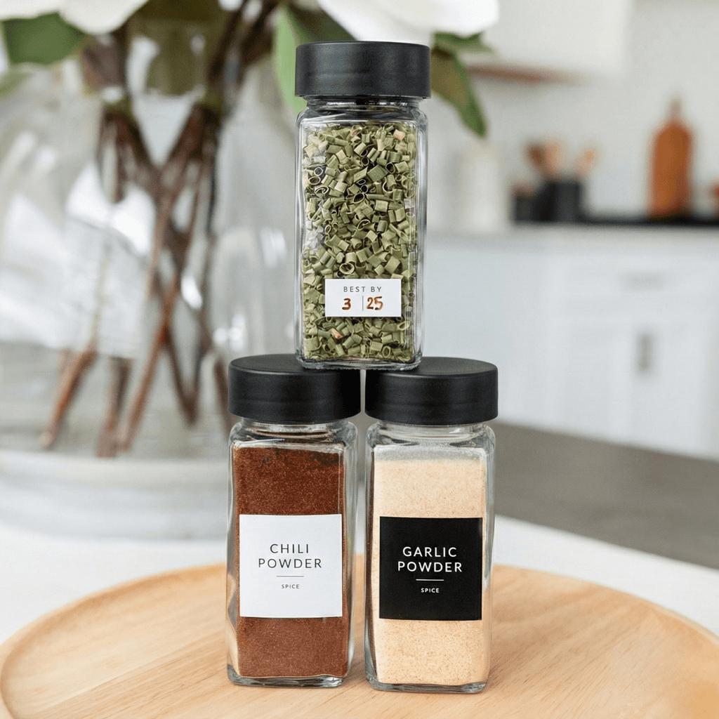 Stacked spice jars with black lids and a best-by label