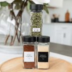 Stacked spice jars with black lids and a best-by label