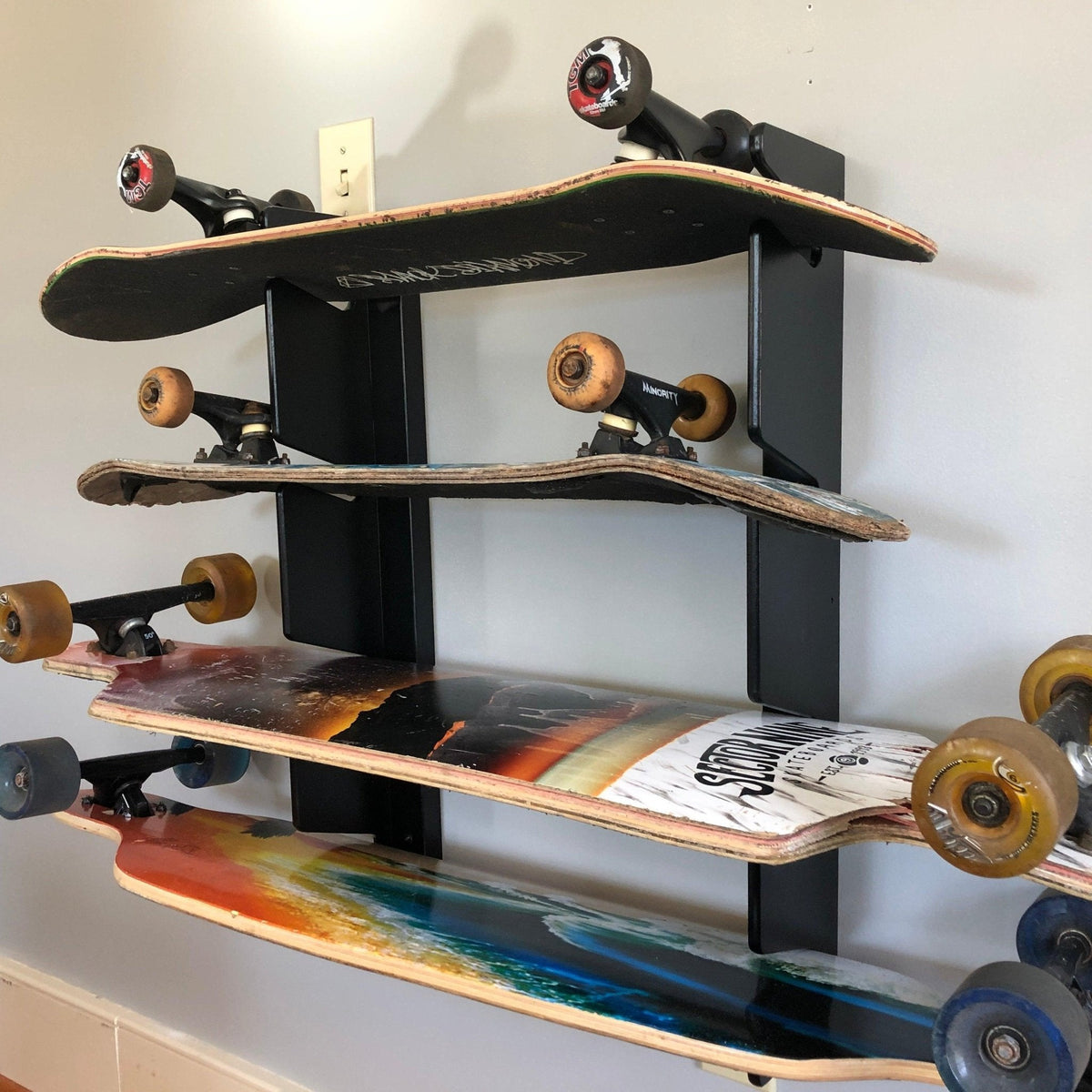 Skateboard wall organizer holding four skateboards