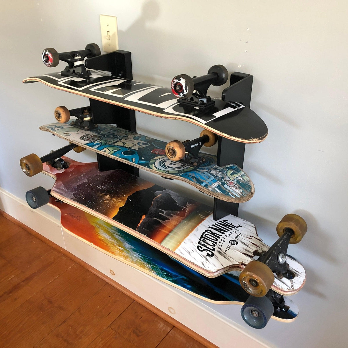 Skateboard organizer holding four longboards and skateboards