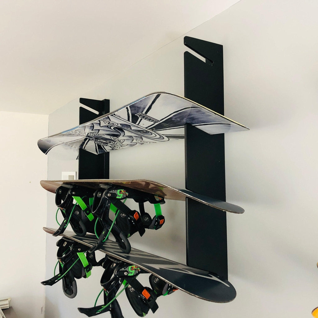 Snowboard wall rack holding three snowboards with bindings
