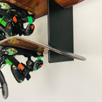 Snowboards with bindings resting on the black wall rack