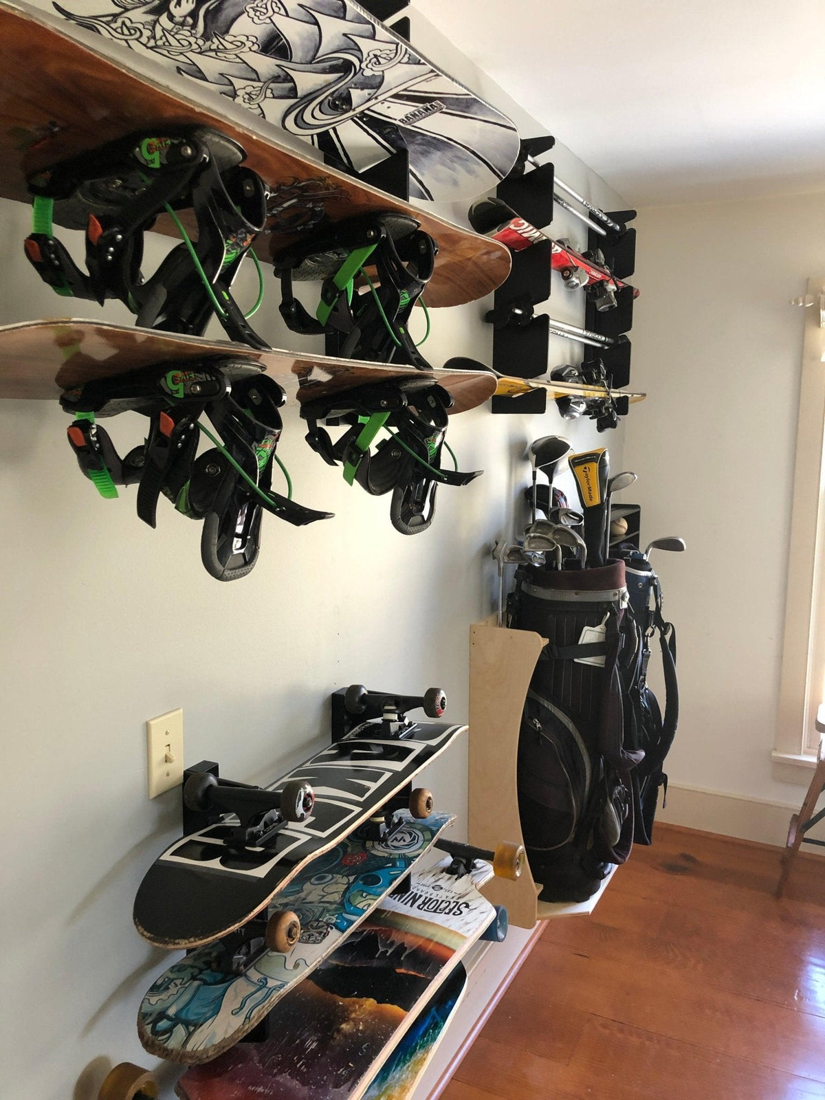 Snowboard rack holding snowboards above skateboards and golf bags