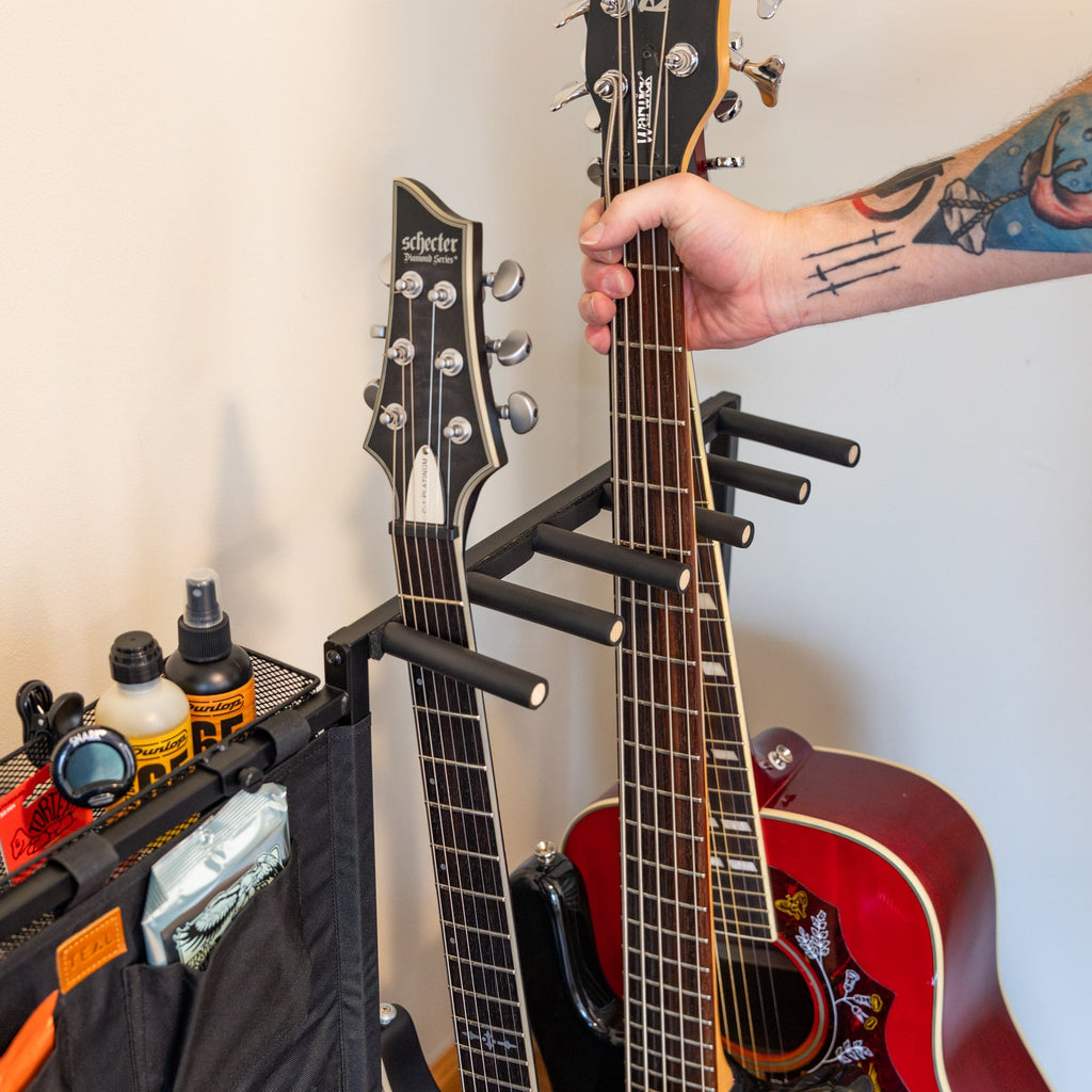 Hand placing a guitar in the rack beside a storage pouch