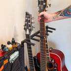 Hand placing a guitar in the rack beside a storage pouch