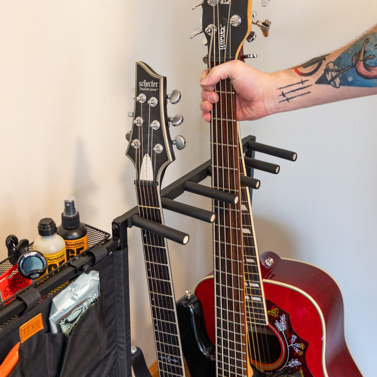 Hand placing a guitar in the rack beside a storage pouch
