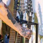 Hand lifting a guitar from the gray rack slot