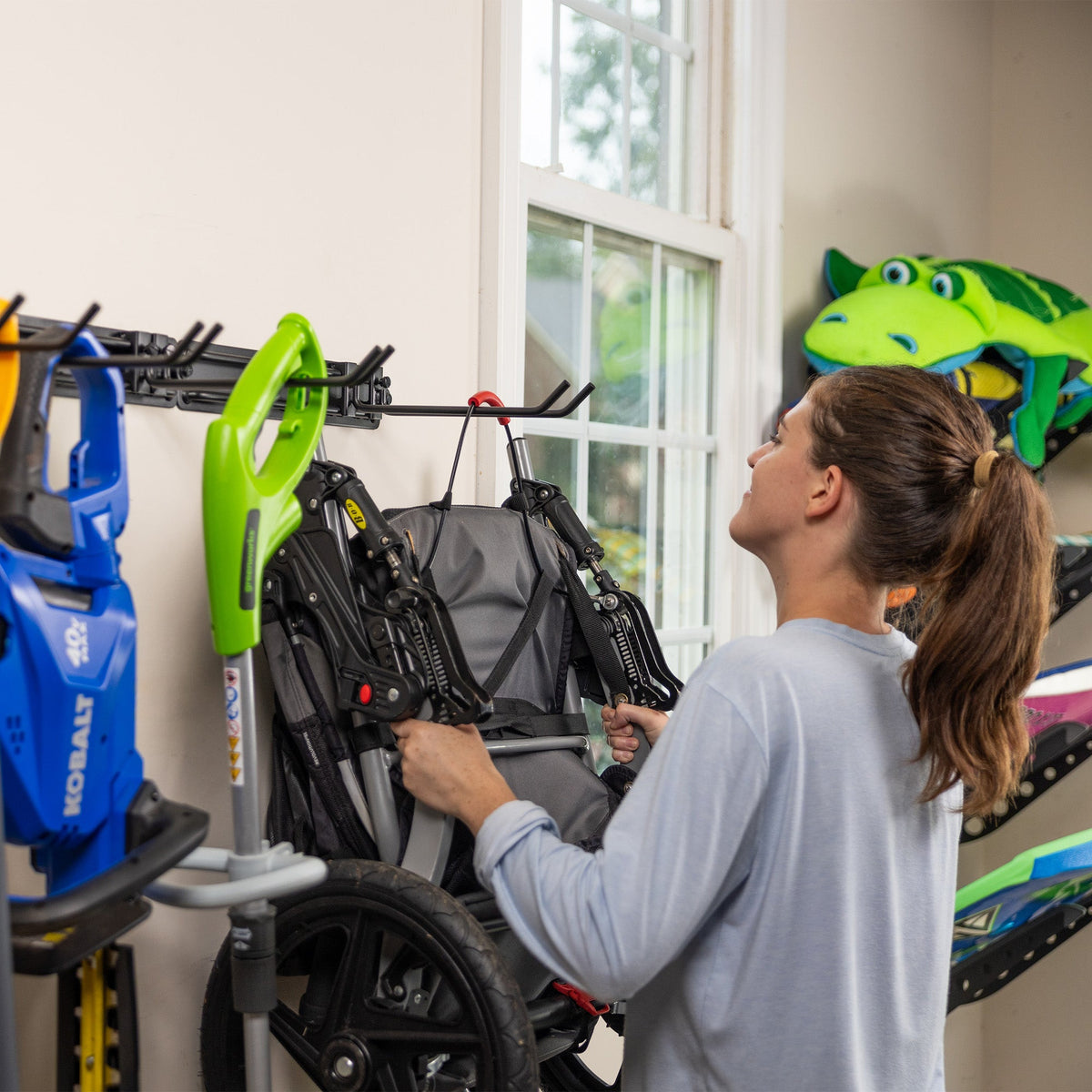 Woman hanging a folded camping chair on the wall organizer beside sports gear