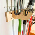 Hook rack holding a hose and long-handled tools on a wall