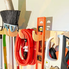 Heavy-duty hook rack holding a broom, extension cords, a level and ear protection