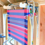 Striped folding beach chair hanging on a lawn chair hook