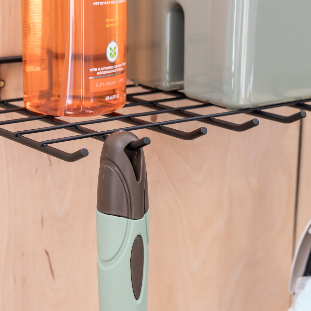 Close-up of a spray bottle hanging from a small hook under the shelf