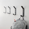 Four black Crozet wall hooks with a backpack hanging on one