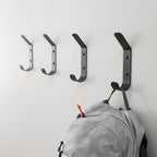 Four black Crozet wall hooks with a backpack hanging on one