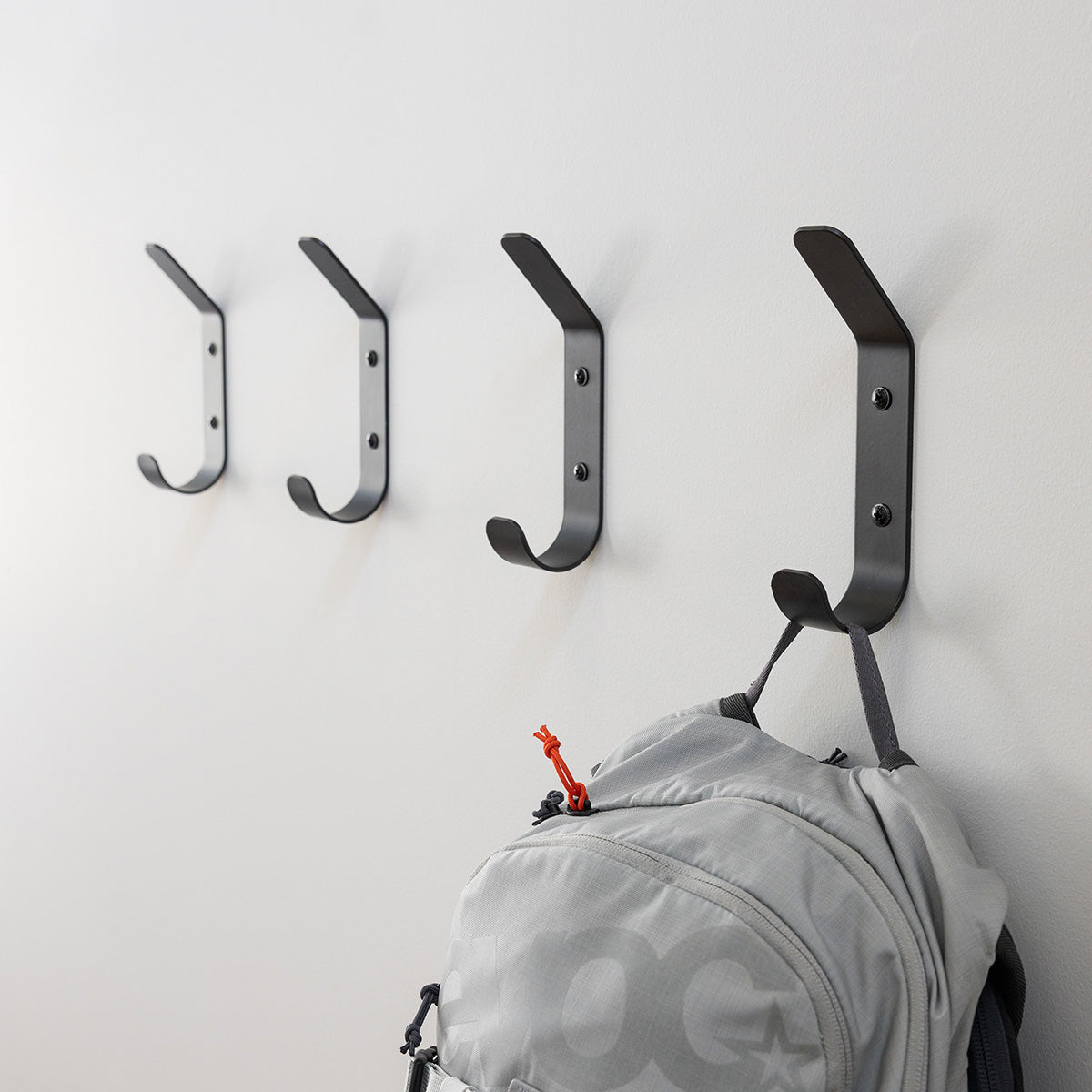 Four black Crozet wall hooks with a backpack hanging on one